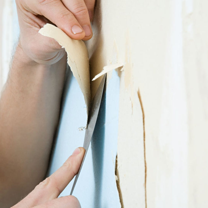 close up of a person scraping pale wallpaper