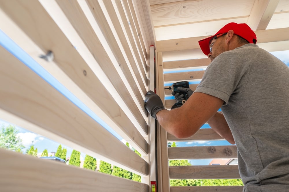 man in a red hat and gray t shirt screwing together wooden planks