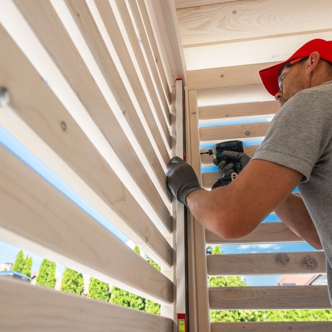 man in a red hat and gray t shirt screwing together wooden planks