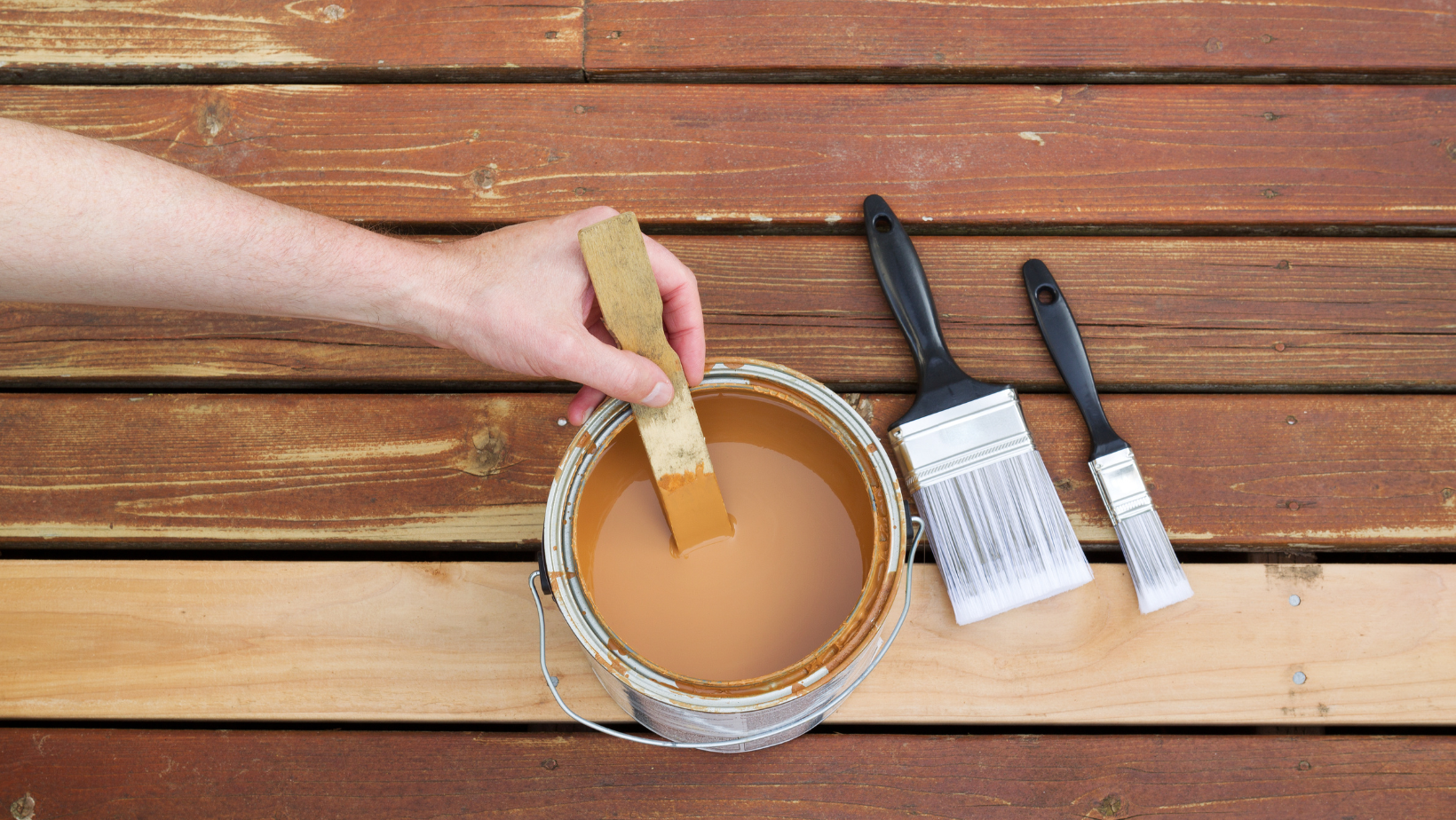 can of wood stain and brushes on a wooden deck