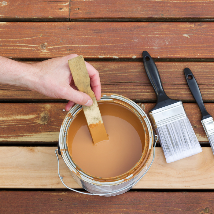 can of wood stain and brushes on a wooden deck