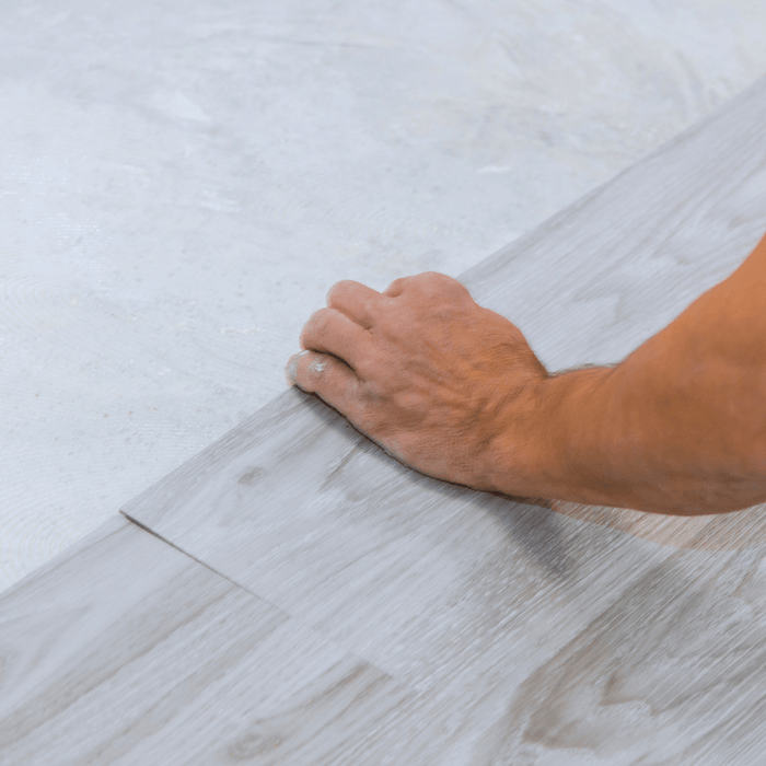 carpenter installing gray vinyl wood plank flooring