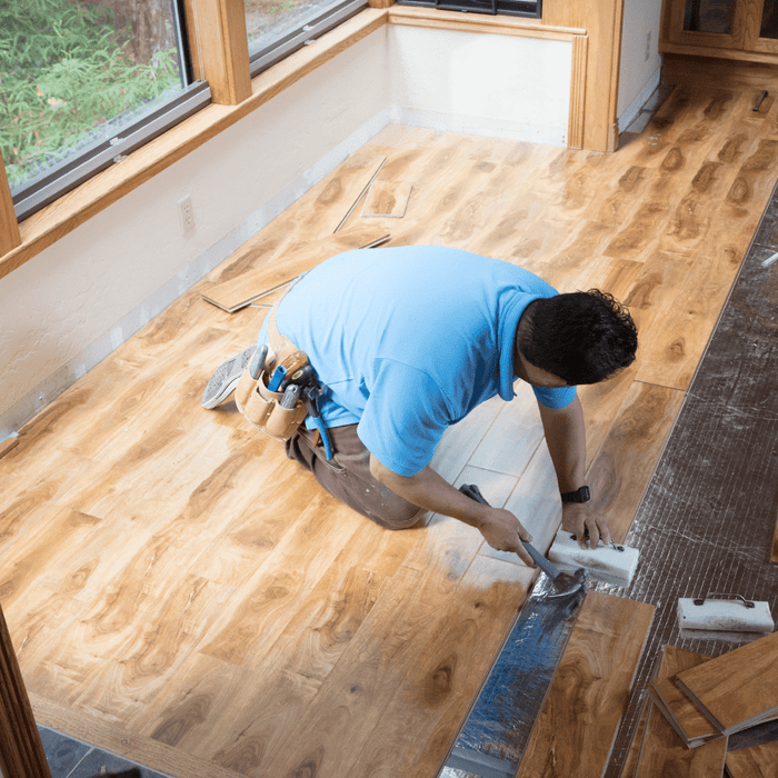 carpenter in a blue polo patching a wooden floor